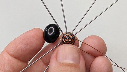 Black and rose bead component lying atop ornament frame